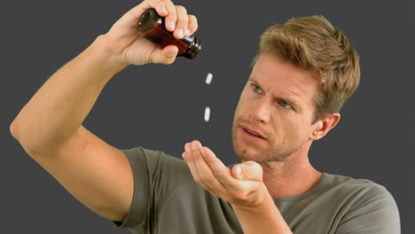 Man-pouring-out-pills-on-grey-screen