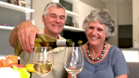 Smiling-man-pouring-glass-of-white-wine-for-his-wife
