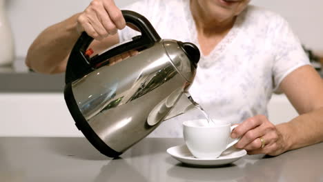 Woman-pouring-boiling-water-from-kettle-into-cup