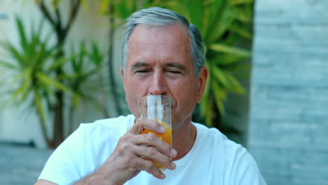 Retired-man-drinking-orange-juice-outside