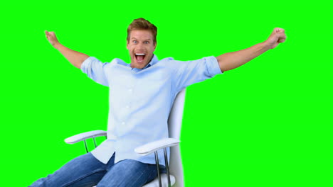 Mann-Sitzt-Auf-Drehstuhl-Mit-Erhobenen-Armen,-Um-Seinen-Erfolg-Auf-Einem-Greenscreen-Zu-Zeigen