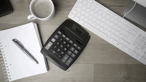 Calculator-falling-on-office-desk-in-black-and-white