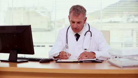 Smiling-doctor-writing-on-his-notebook-