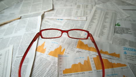 Glasses-falling-over-sheets-of-paper-showing-yellow-charts