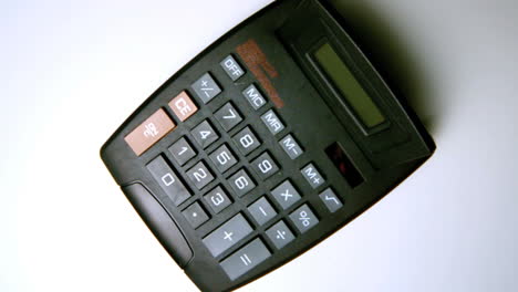 Black-calculator-falling-on-white-surface