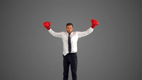 Geschäftsmann-In-Boxhandschuhen-Springt-Und-Schlägt-Mit-Den-Fäusten-Auf-Grauem-Hintergrund
