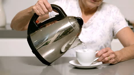 Frau-Gießt-Heißes-Wasser-Aus-Wasserkocher-In-Tasse