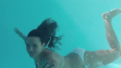 Lächelnde-Brünette-Schwimmt-Unter-Wasser-Und-Schaut-In-Die-Kamera