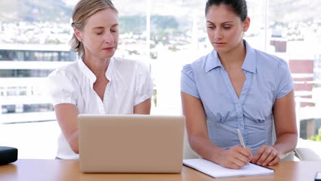 Two-businesswomen-working-together-while-using-a-laptop