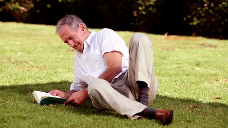 Mature-man-laying-on-the-grass-and-reading-a-book