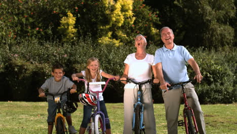 Mehrgenerationenfamilie-Posiert-Mit-Ihren-Fahrrädern-In-Einem-Park-