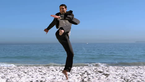 Un-Apuesto-Hombre-De-Negocios-Saltando-Y-Pateando-En-La-Playa.