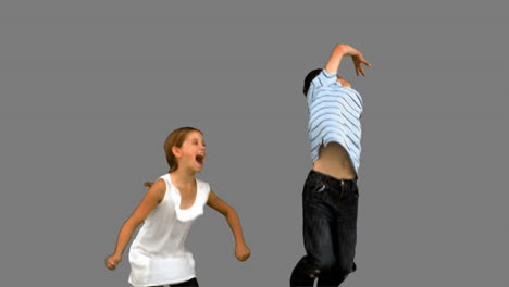 Siblings-jumping-together-on-grey-screen