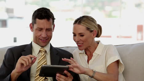 Colleagues-laughing-together-while-working-on-a-tablet