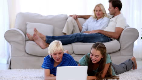 Parents-relaxing-on-couch-with-children-using-laptop