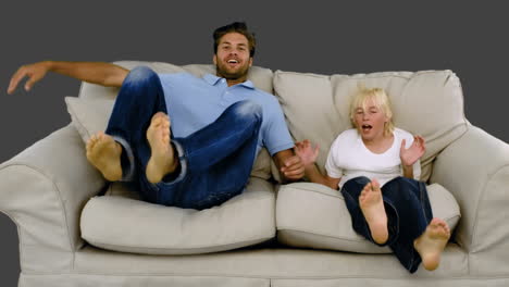 Father-and-son-jumping-on-the-sofa-on-grey-background