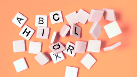 Plastic-letters-bouncing-and-showing-alphabet-on-orange-surface
