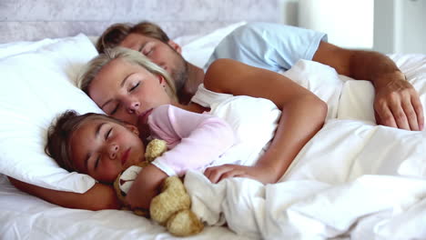 Parents-and-daughter-holding-teddy-bear-sleeping-peacefully