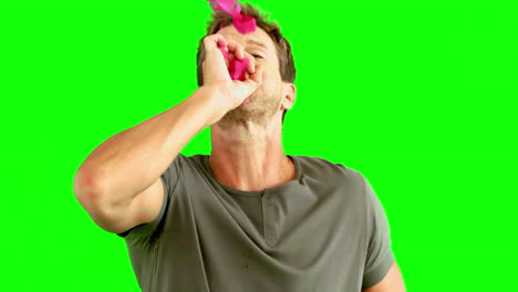 Man-blowing-pink-confetti-on-green-screen