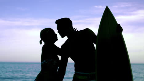 Man-with-surfboard-kissing-girlfriend-on-the-beach