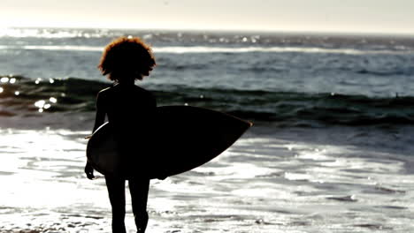 Silhouette-Einer-Frau,-Die-Mit-Ihrem-Surfbrett-Am-Strand-Läuft