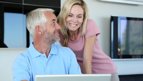 Man-using-his-laptop-with-his-wife