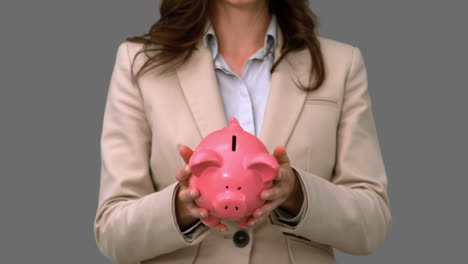 Businesswoman-throwing-a-piggy-bank-on-grey-screen