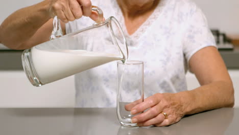 Woman-pouring-glass-of-milk-in-the-kitchen