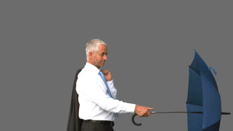 Businessman-going-under-his-umbrella-on-grey-screen