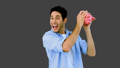 Man-shaking-piggy-bank-excitedly-on-grey-background