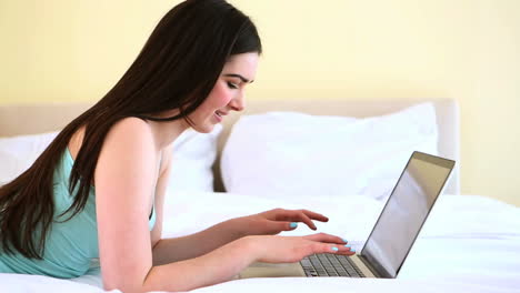 Cheerful-woman-typing-on-her-laptop-