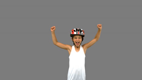Cute-girl-wearing-a-bike-helmet-and-raising-arms-on-grey-screen