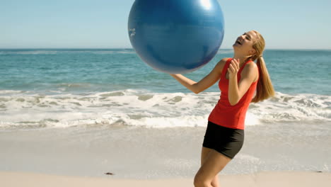 Glückliche-Frau-Spielt-Mit-Ihrem-Fitness-Ball-Am-Strand-