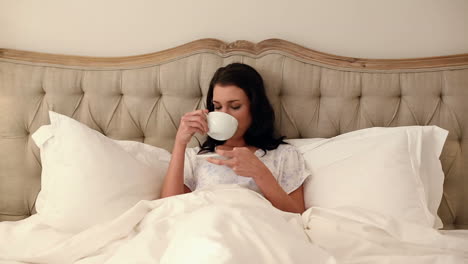 Beautiful-brunette-lying-in-bed-drinking-coffee