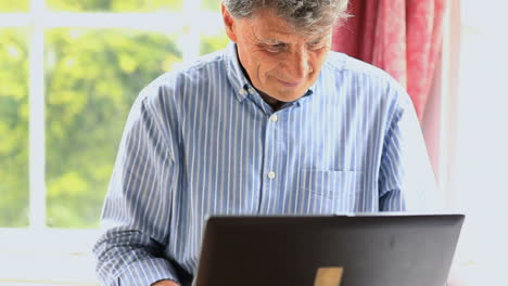 Mature-man-sitting-by-a-window-using-his-computer