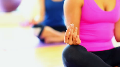 Mid-section-on-meditating-young-women-sitting-on-exercise-mats