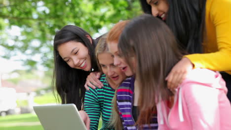 Female-students-looking-at-the-laptop-together-outside-and-laughing