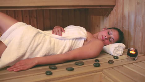 Brunette-wearing-a-towel-relaxing-in-the-sauna