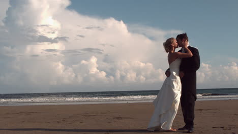 Feliz-Pareja-De-Recién-Casados-Besándose-En-La-Playa