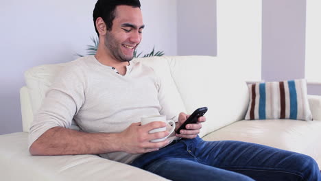 Handsome-man-sending-a-text-drinking-coffee