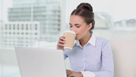 Young-businesswoman-working-on-her-laptop-drinking-coffee