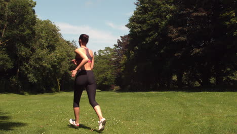 Rear-view-of-sporty-woman-running-on-grass