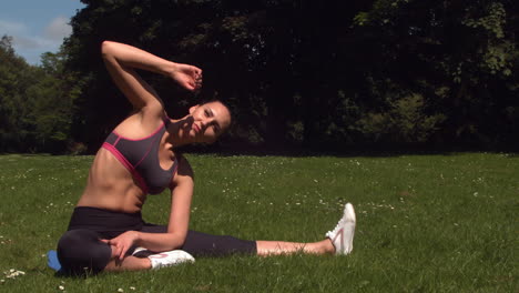 Sporty-brunette-stretching-on-grass