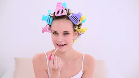 Young-model-in-hair-rollers-putting-on-lip-gloss