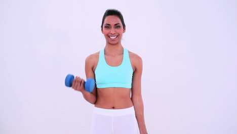 Fit-woman-lifting-hand-weights-and-smiling-at-camera