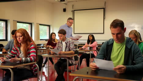 Profesor-Entregando-Trabajos-A-Sus-Alumnos-En-El-Aula