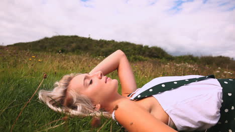 Attractive-happy-blonde-lying-down-on-lawn