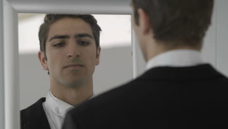 Nervous-groom-looking-to-mirror-adjusting-tie
