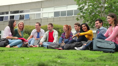 Estudiantes-Felices-Sentados-En-El-Césped-Juntos-Hablando