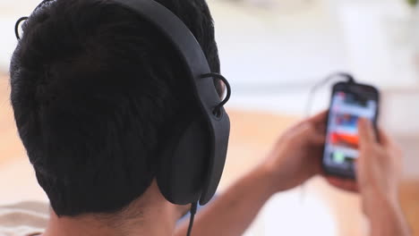 Gutaussehender-Mann-Mit-Kopfhörern,-Der-Auf-Seinem-Smartphone-Musik-Auswählt